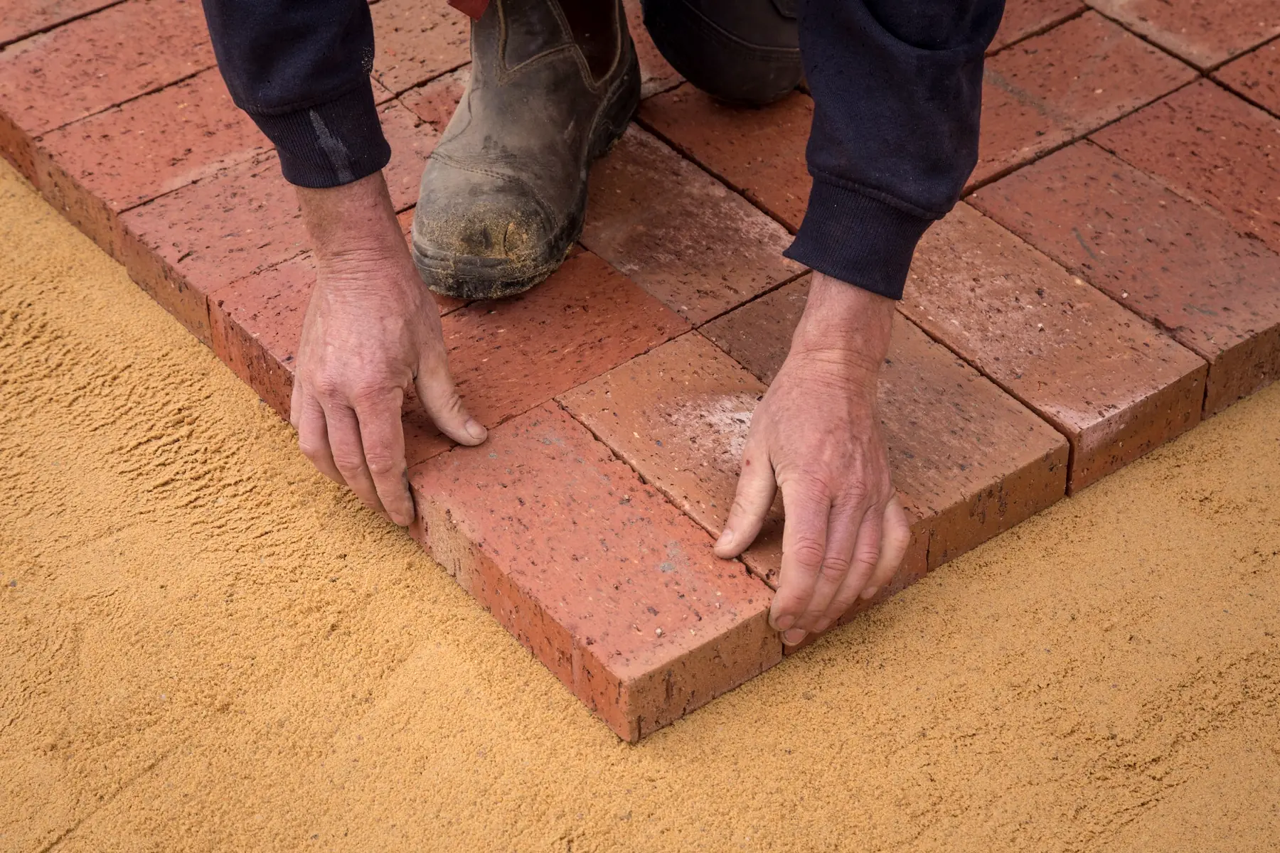A landscaper sets pavers for a new patio.
