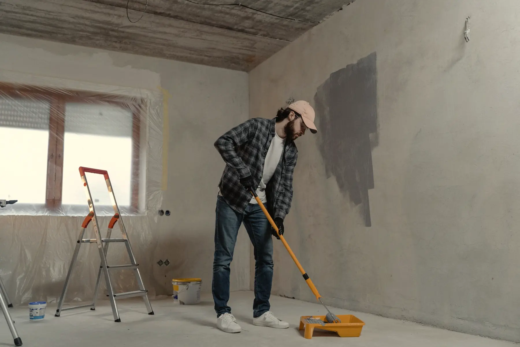 A painter rolls a fresh coat onto an interior wall.