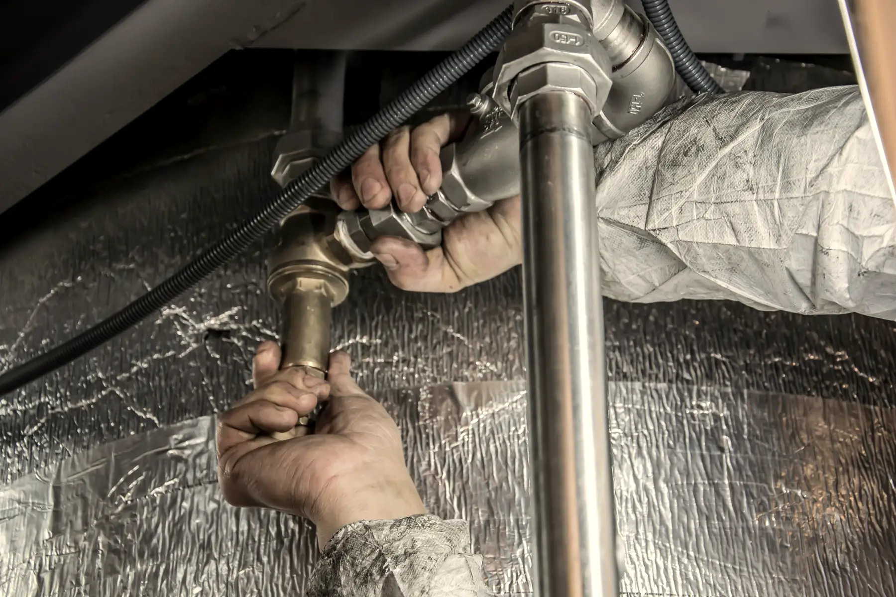 A plumber tightens a fitting on a water line.